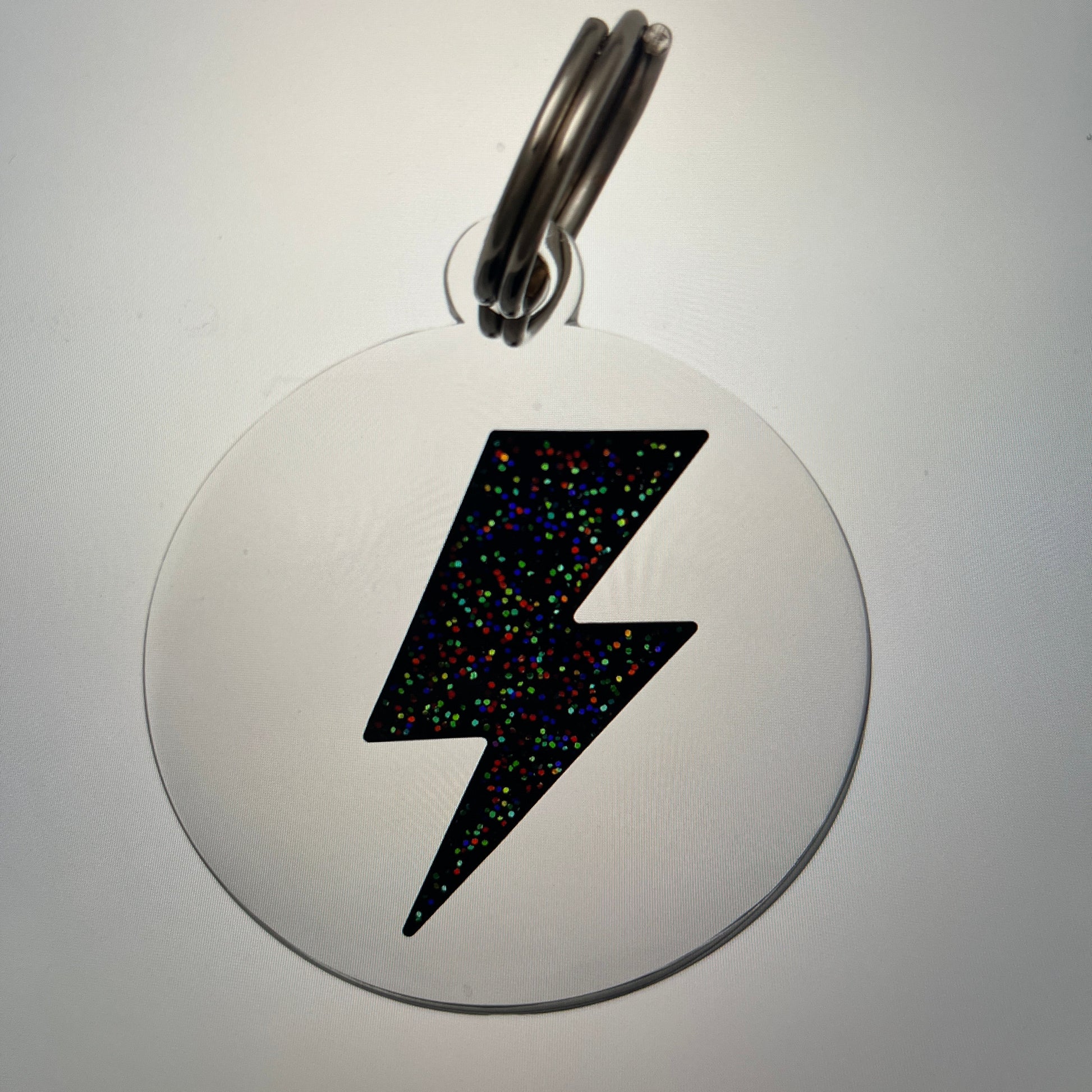 Circular metal badge with a black lightning bolt design on a white background
